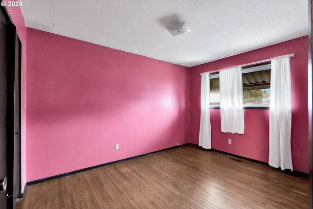 spare room featuring hardwood / wood-style floors and a textured ceiling