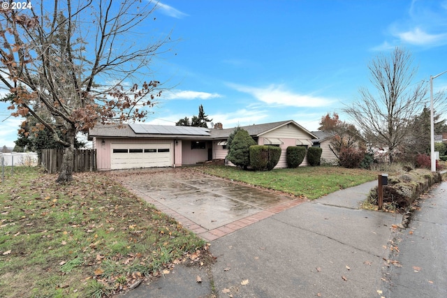 single story home with a front lawn, a garage, and solar panels