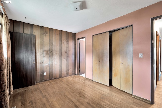 unfurnished bedroom with wood walls and light hardwood / wood-style floors