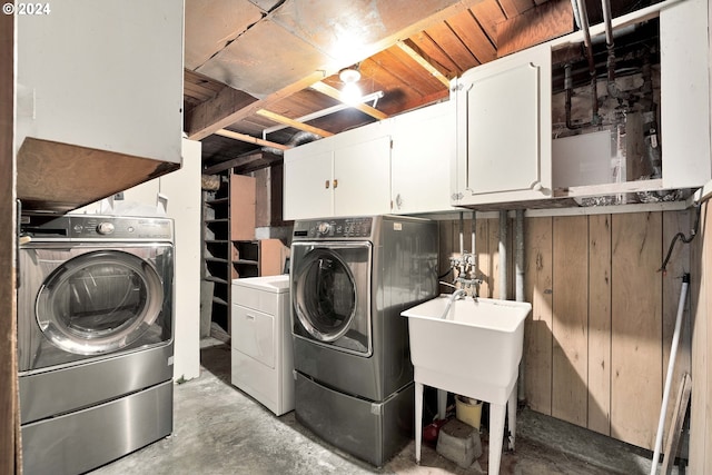 clothes washing area with wooden walls, cabinets, and independent washer and dryer