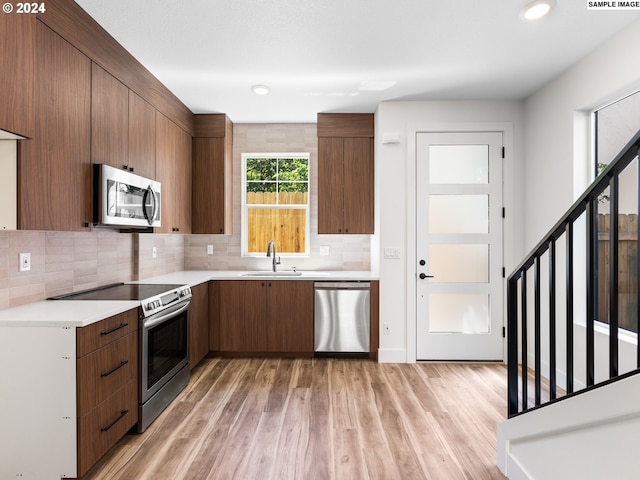 kitchen with light wood-type flooring, sink, appliances with stainless steel finishes, and decorative backsplash