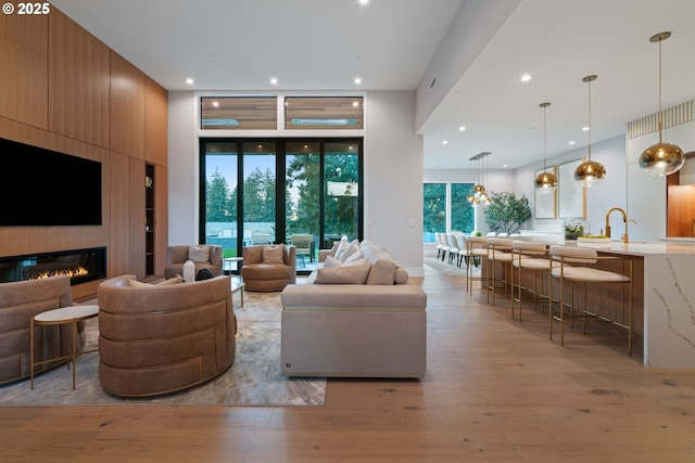 living room featuring a high ceiling, a large fireplace, and light hardwood / wood-style floors