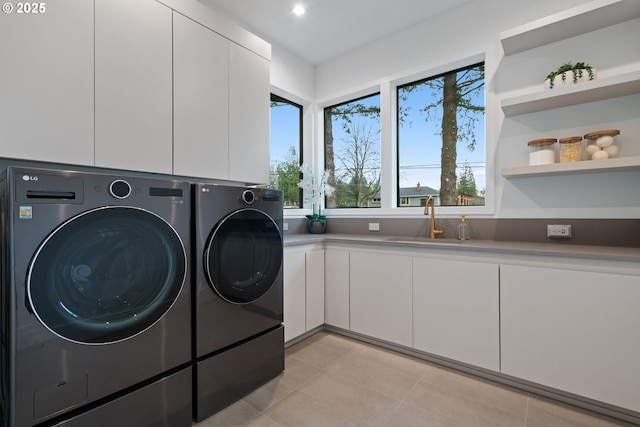 clothes washing area with sink, cabinets, and washer and dryer