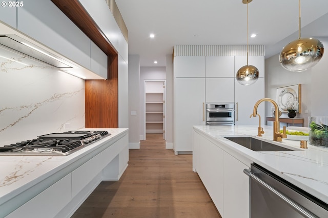 kitchen featuring pendant lighting, sink, white cabinetry, backsplash, and stainless steel appliances