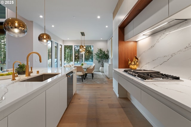 kitchen featuring pendant lighting, sink, white cabinets, stainless steel appliances, and light stone countertops