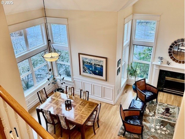 living area featuring light wood finished floors, a wainscoted wall, and a high end fireplace