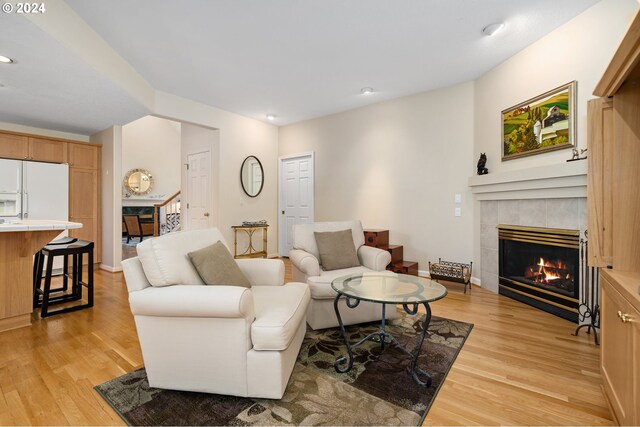 living room featuring a tiled fireplace and light hardwood / wood-style floors