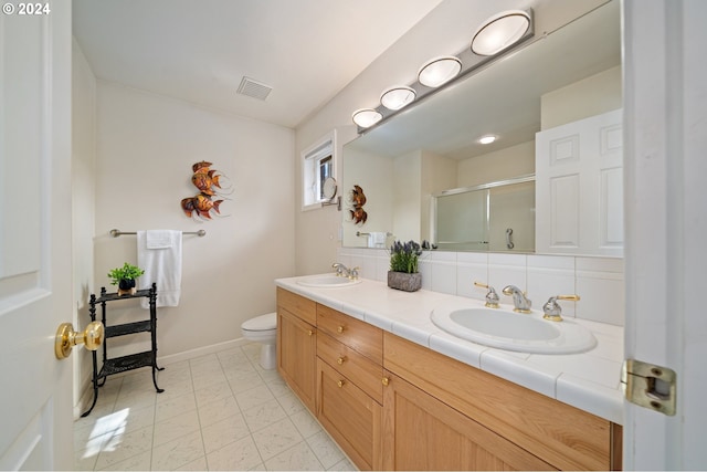 bathroom with vanity, a shower with shower door, toilet, and tasteful backsplash