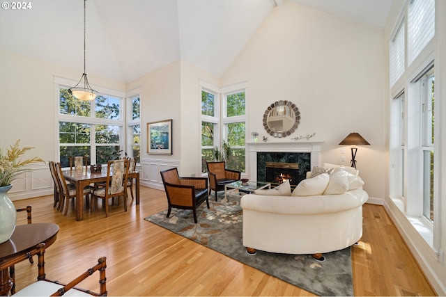 living area featuring a premium fireplace, light wood-style floors, high vaulted ceiling, and a wealth of natural light