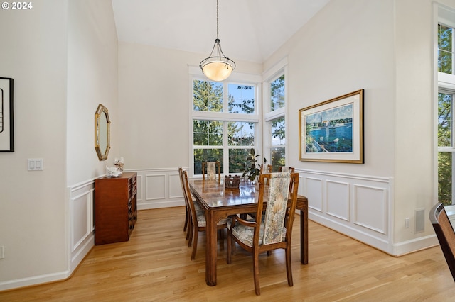 dining area with a decorative wall, a wainscoted wall, and light wood-type flooring