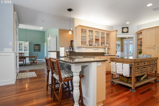 kitchen with dark wood-type flooring, a kitchen breakfast bar, decorative light fixtures, and kitchen peninsula