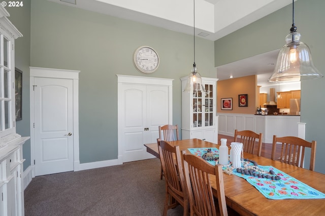 dining area featuring a high ceiling and dark colored carpet