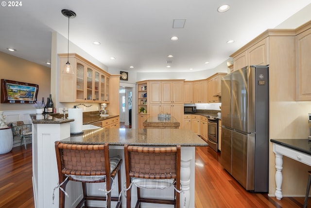 kitchen with a breakfast bar, hardwood / wood-style floors, decorative light fixtures, kitchen peninsula, and stainless steel appliances