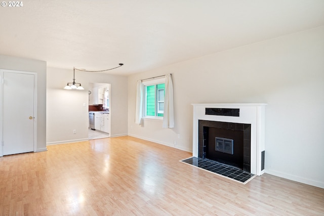 unfurnished living room featuring a tile fireplace and light hardwood / wood-style floors