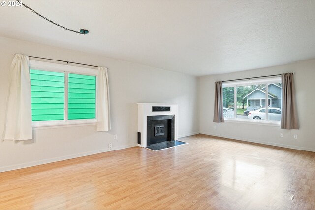 unfurnished living room featuring a textured ceiling and light hardwood / wood-style flooring