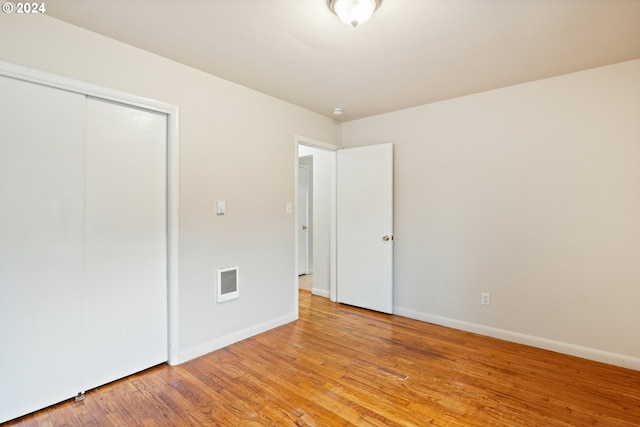 unfurnished bedroom with light wood-type flooring and a closet