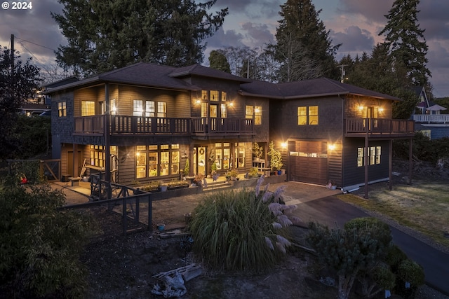 back house at dusk featuring a balcony and a garage