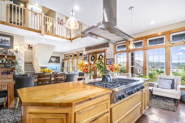 kitchen with open floor plan, a towering ceiling, stainless steel gas cooktop, and island exhaust hood
