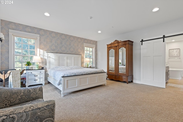 carpeted bedroom with connected bathroom and a barn door