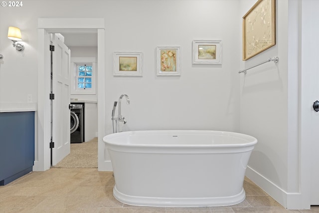 bathroom featuring a bathing tub, washer / dryer, and tile patterned floors