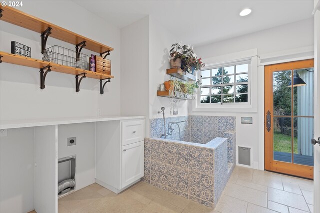 laundry area with cabinets, hookup for an electric dryer, and light tile patterned floors