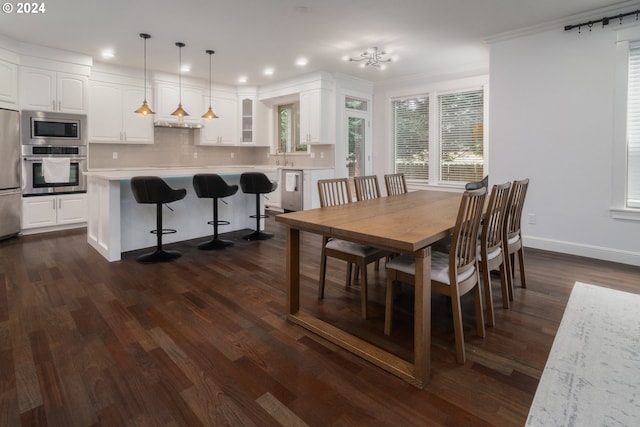 dining area featuring ornamental molding, dark hardwood / wood-style flooring, and sink