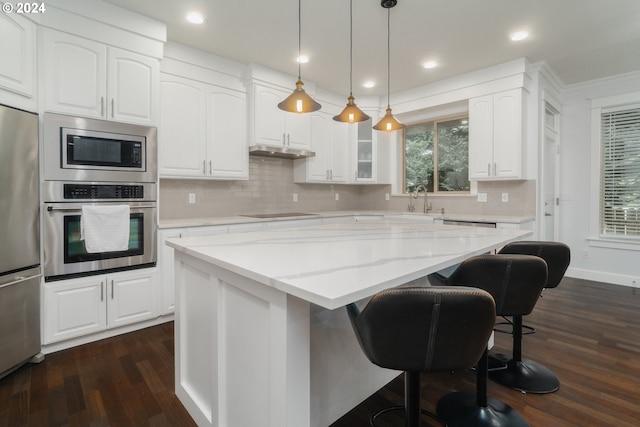 kitchen featuring built in appliances, light stone countertops, a center island, and dark wood-type flooring