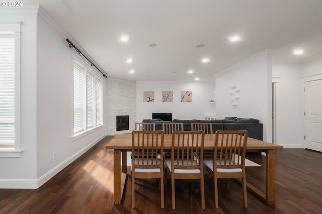 dining room with crown molding, plenty of natural light, dark hardwood / wood-style flooring, and a fireplace