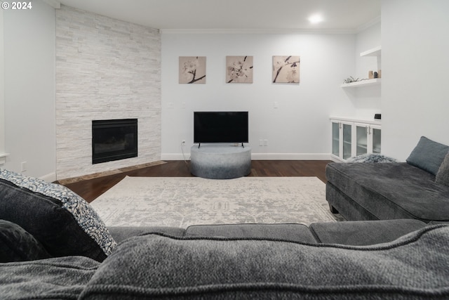 living room featuring built in features, ornamental molding, hardwood / wood-style flooring, and a fireplace