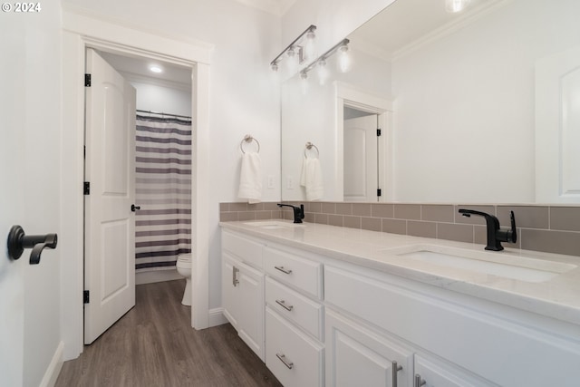 bathroom featuring vanity, hardwood / wood-style floors, toilet, ornamental molding, and decorative backsplash