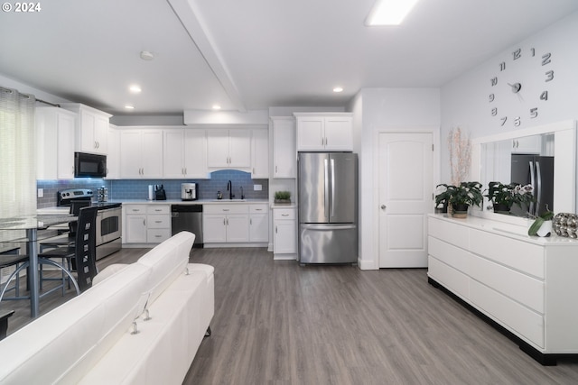 kitchen with wood-type flooring, tasteful backsplash, stainless steel appliances, sink, and white cabinetry