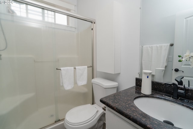 bathroom featuring vanity, toilet, and a shower with shower door