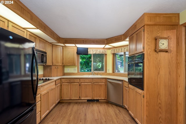 kitchen featuring black appliances, light countertops, a sink, and light wood finished floors