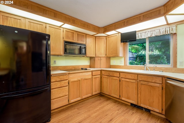 kitchen with light wood-style floors, light countertops, a sink, and black appliances