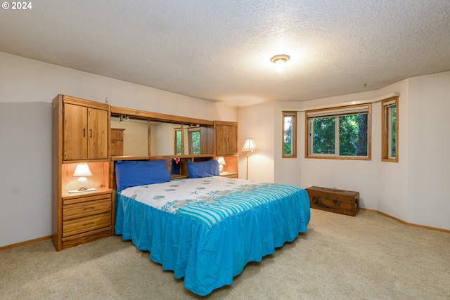 bedroom with light carpet, a textured ceiling, and baseboards