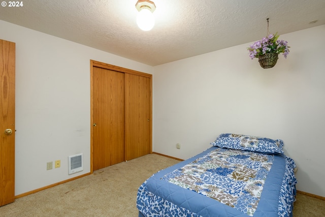 carpeted bedroom with a textured ceiling, a closet, visible vents, and baseboards