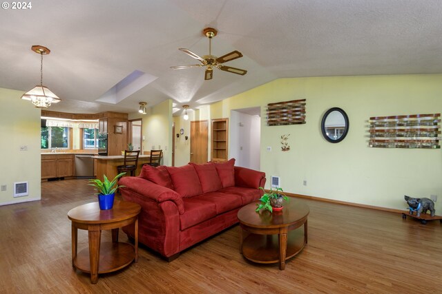 living room featuring wet bar, vaulted ceiling, ceiling fan with notable chandelier, and dark wood-type flooring