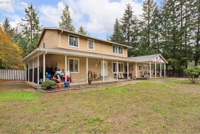 back of property with covered porch and a lawn