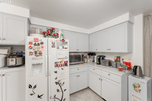 681 Hamlin Dr, Canyonville, OR 97417 - kitchen featuring white fridge with ice dispenser, stainless steel microwave, light countertops, and a textured ceiling