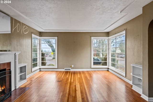 unfurnished living room with a fireplace, a textured ceiling, and hardwood / wood-style flooring