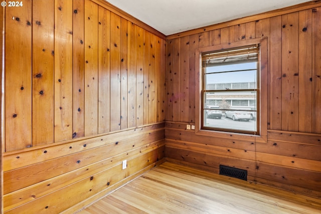 spare room featuring light hardwood / wood-style floors and wooden walls