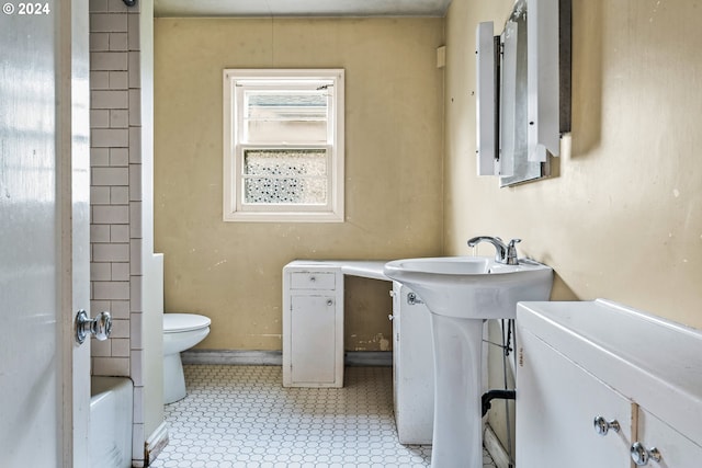 bathroom featuring tile patterned floors, a tub to relax in, toilet, and sink