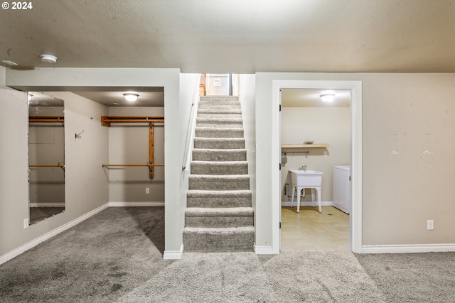 staircase with carpet, sink, and a textured ceiling