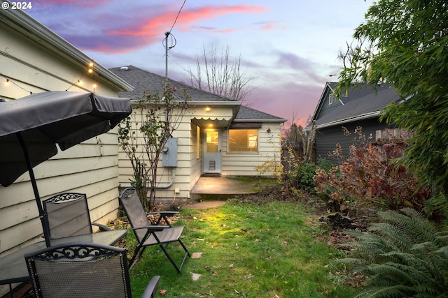 rear view of house with a patio and a lawn