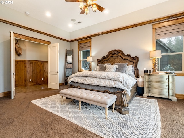 carpeted bedroom featuring ceiling fan and wood walls