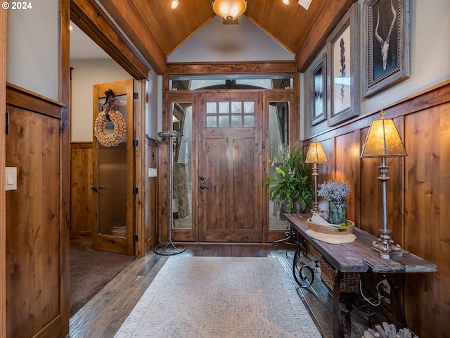 entryway with dark wood-type flooring, vaulted ceiling, wooden ceiling, and wood walls