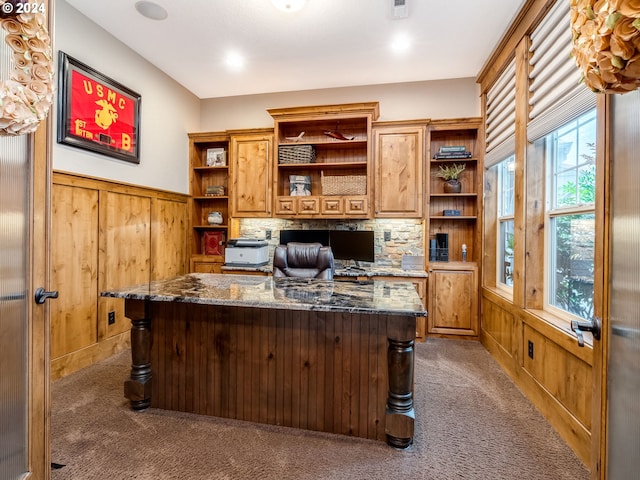 office space featuring wooden walls, carpet, and built in desk