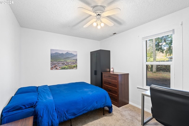 bedroom featuring a textured ceiling, light carpet, and ceiling fan