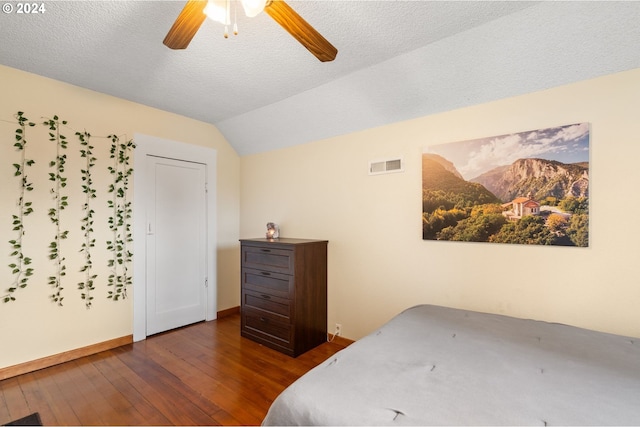 bedroom featuring dark wood-type flooring, ceiling fan, a textured ceiling, and vaulted ceiling