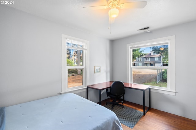 bedroom featuring hardwood / wood-style floors, ceiling fan, and multiple windows